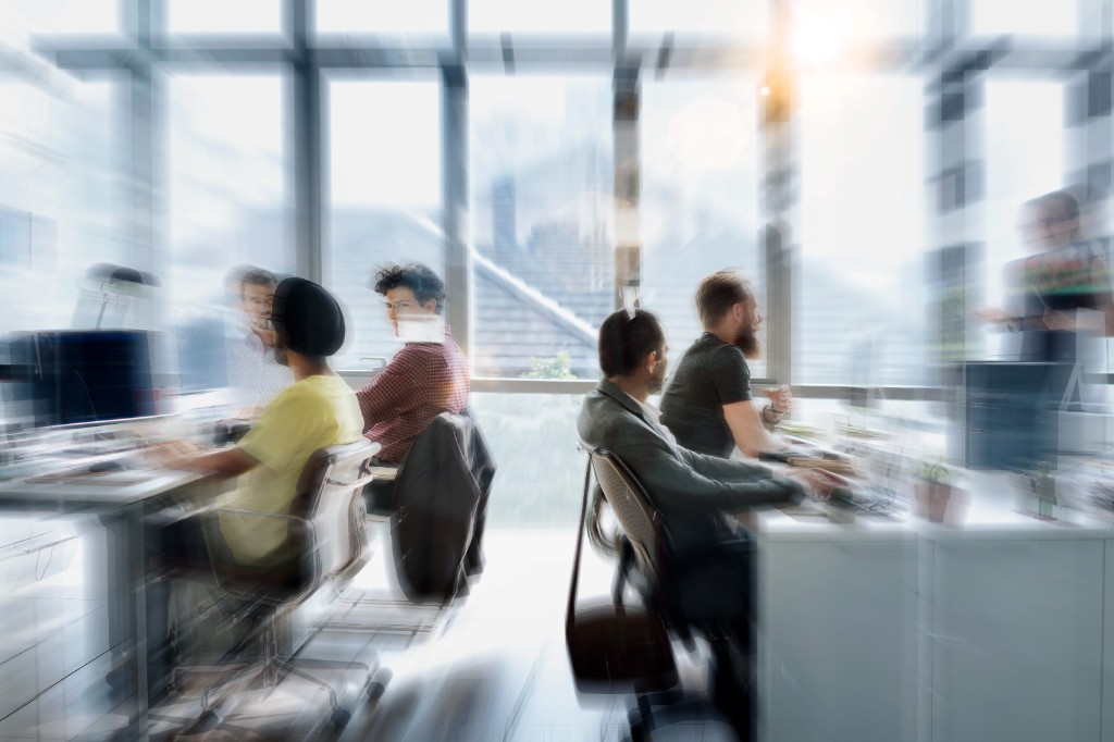People moving through a working office, shown with motion blur.